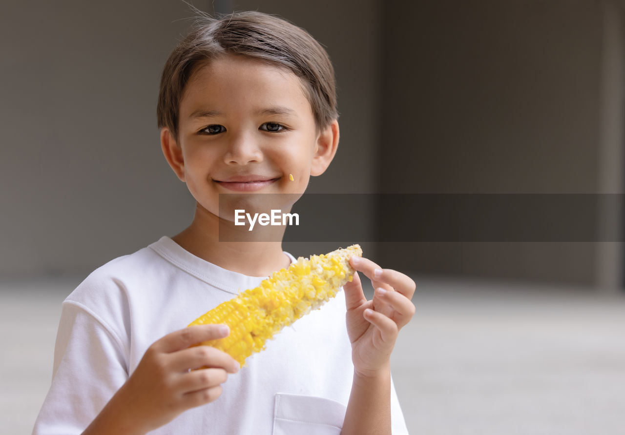 portrait of young woman holding corn at home