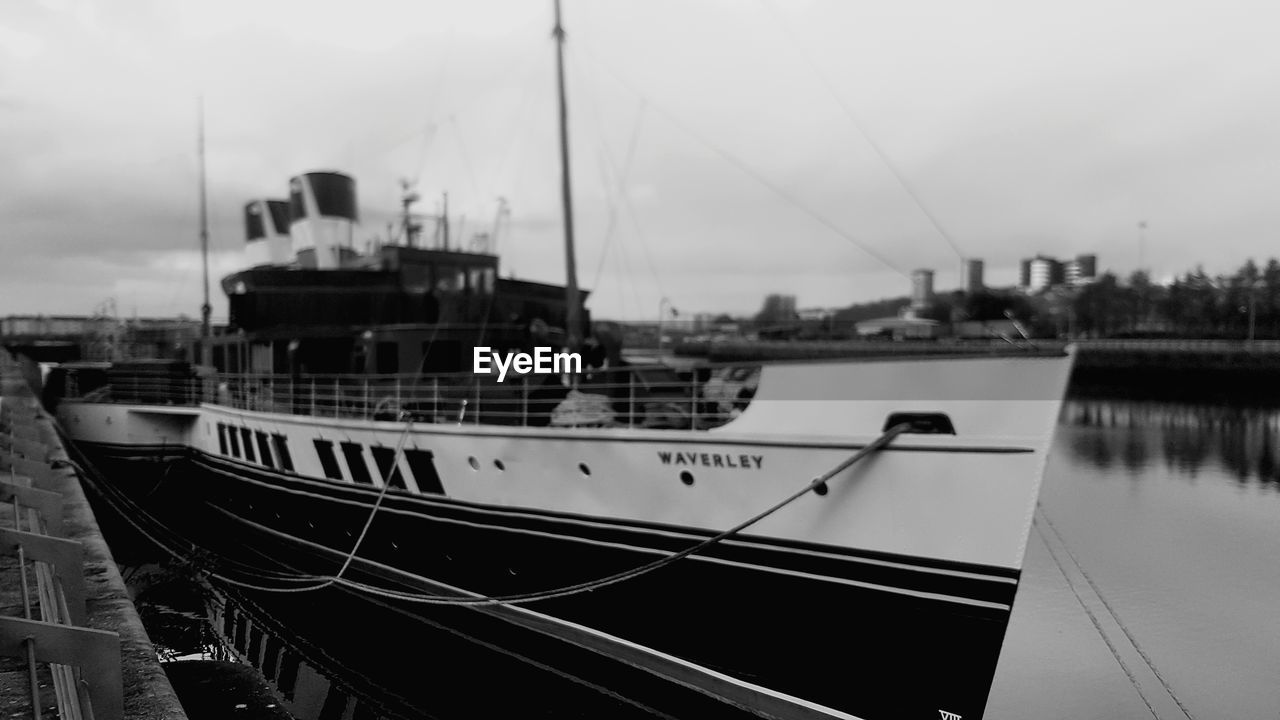 SAILBOAT MOORED AT HARBOR AGAINST SKY