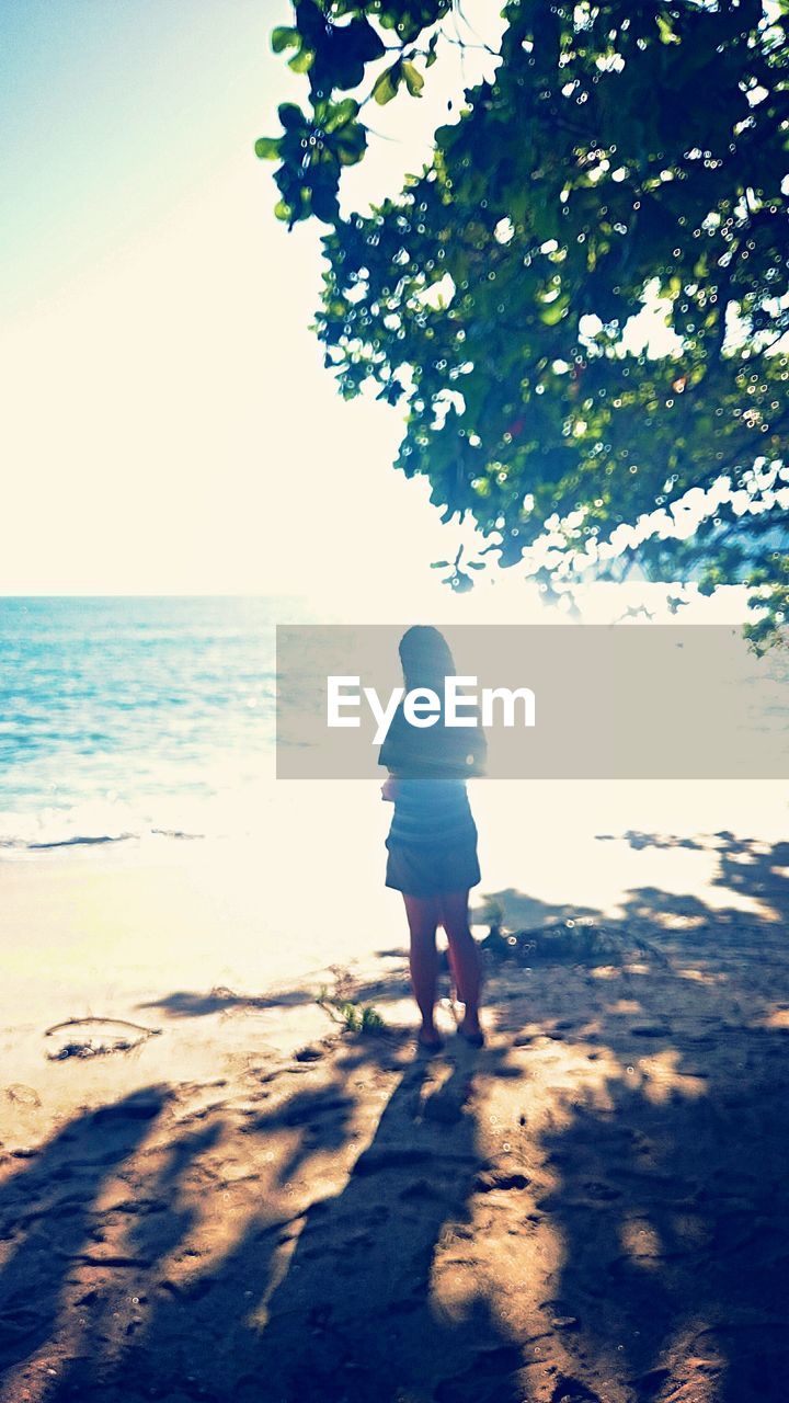 Rear view of woman standing at beach