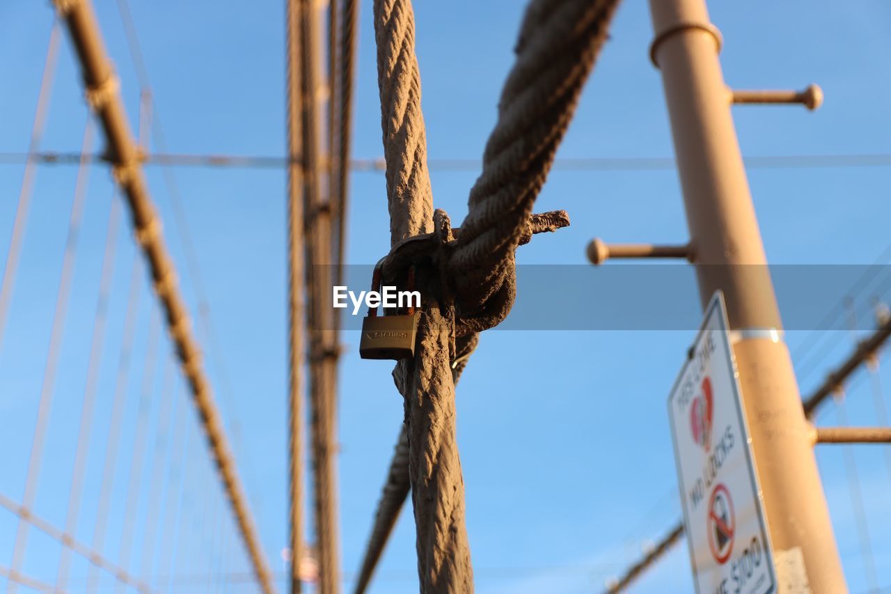 Low angle view of rope tied to pole against sky
