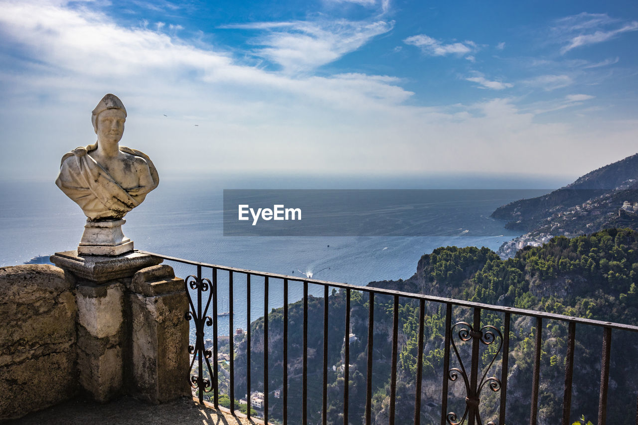 STATUE BY RAILING AGAINST SEA AND SKY