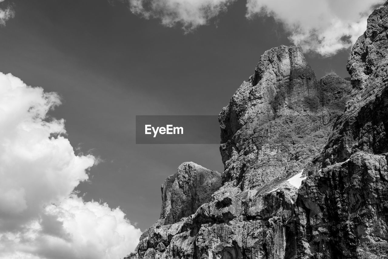 LOW ANGLE VIEW OF ROCK FORMATION AMIDST MOUNTAINS AGAINST SKY