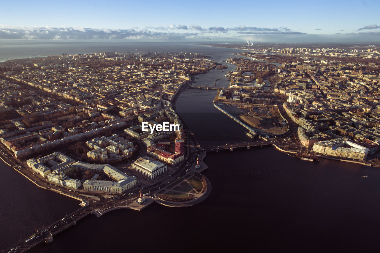 HIGH ANGLE VIEW OF BUILDINGS AND RIVER AGAINST SKY