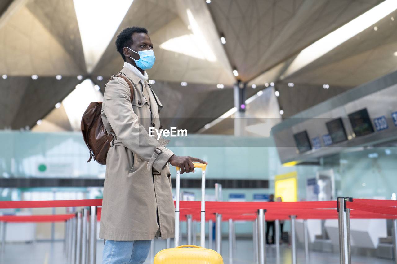 Young businessman wearing mask standing at airport
