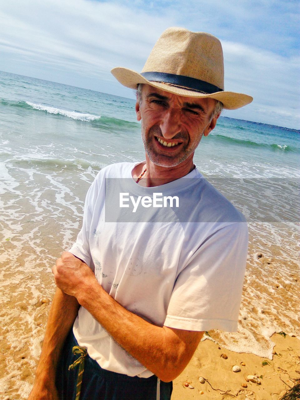 Portrait of mature man wearing hat while standing at beach