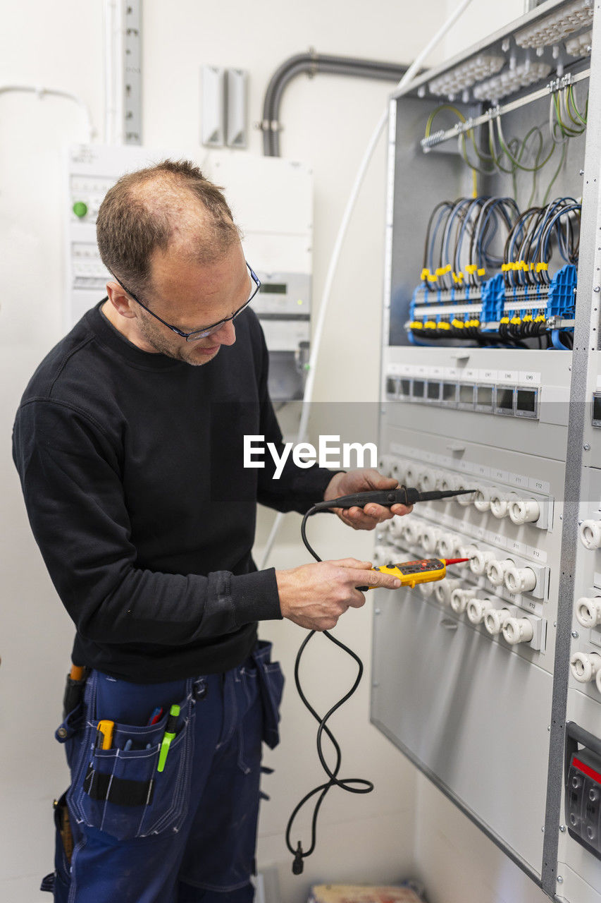 Repairman repairing meter box while working in industry