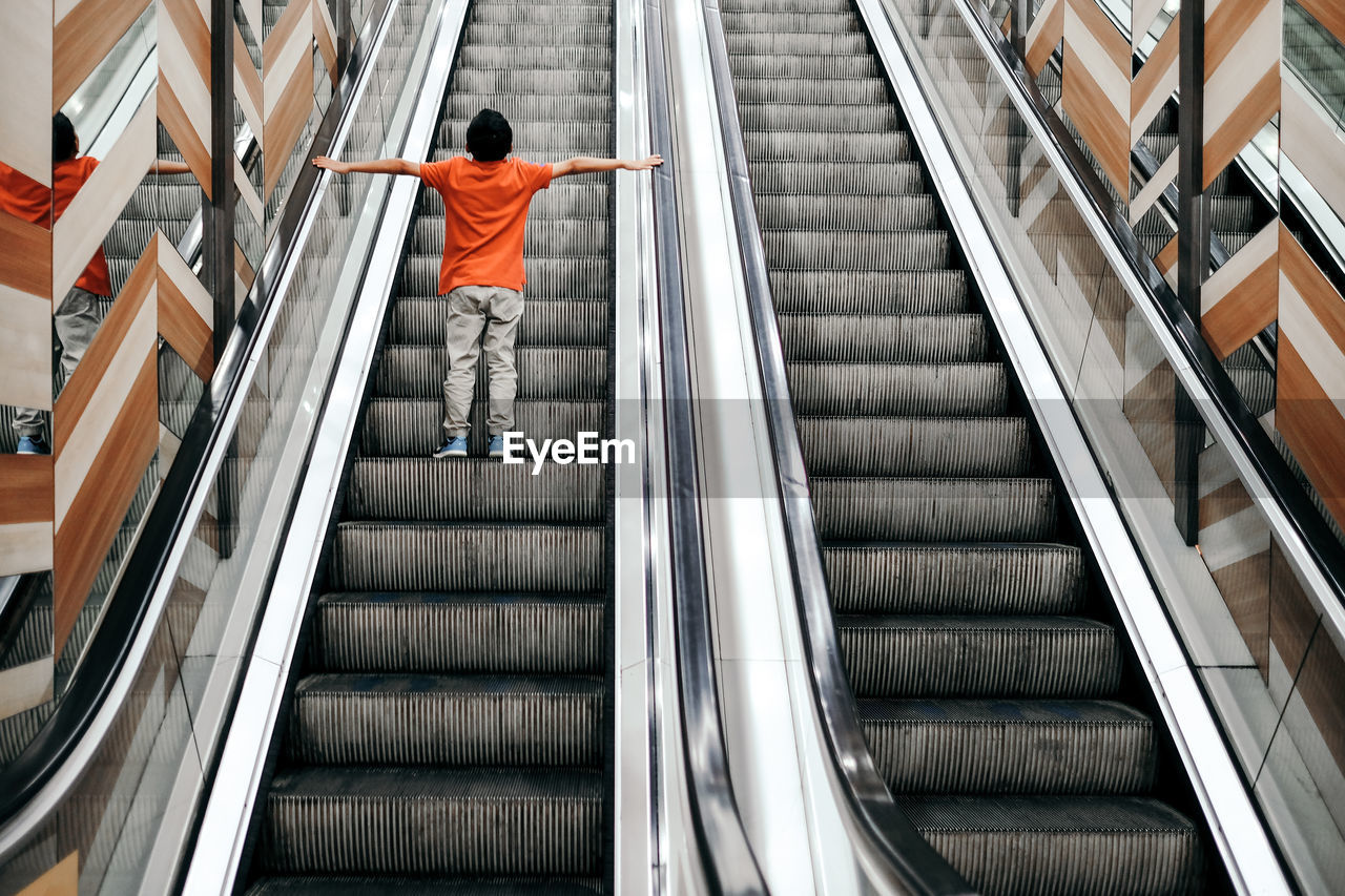 Rear view of boy standing on escalator