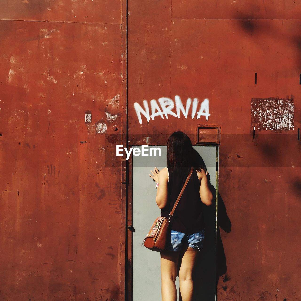 Rear view of woman standing against gate