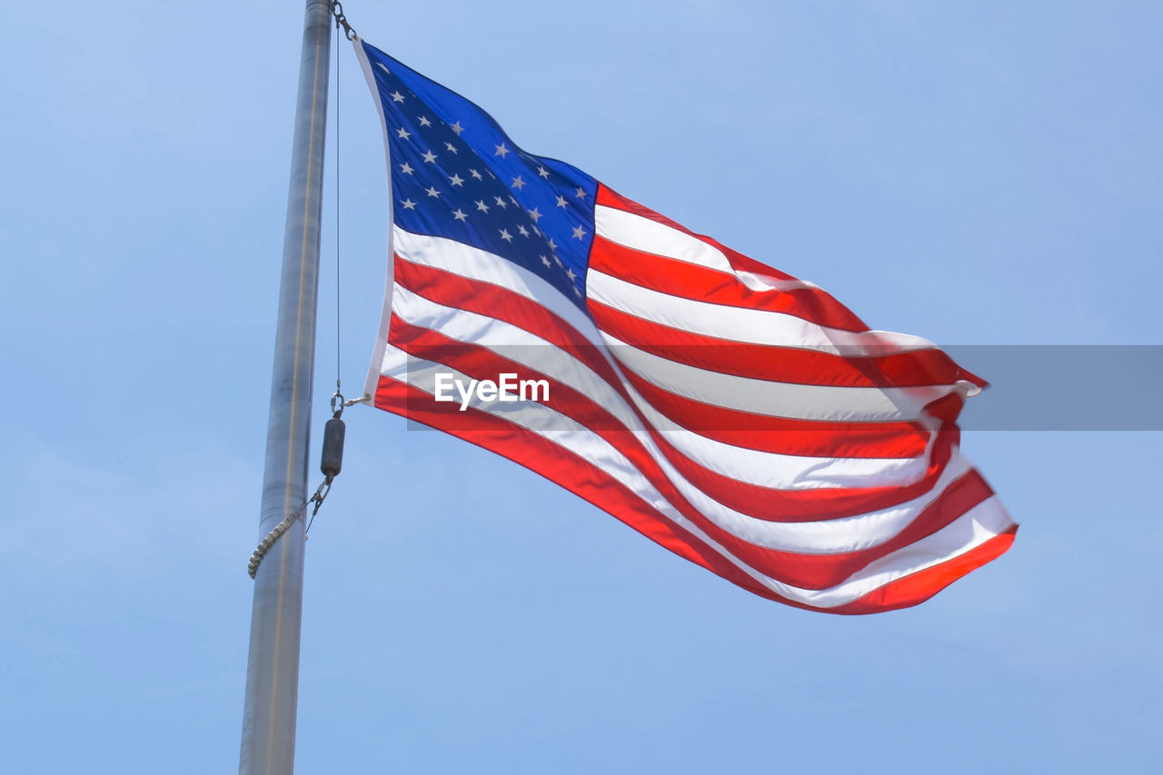 Low angle view of flag against blue sky