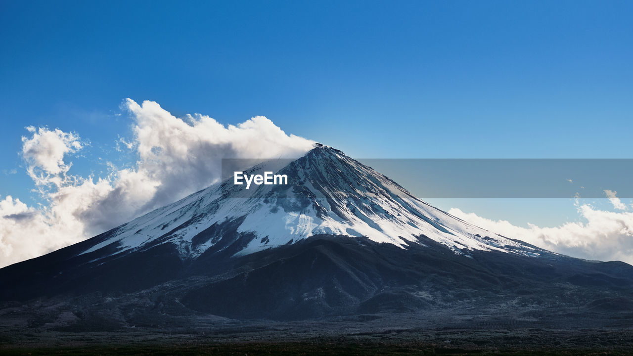 Scenic view of snowcapped mountains against blue sky