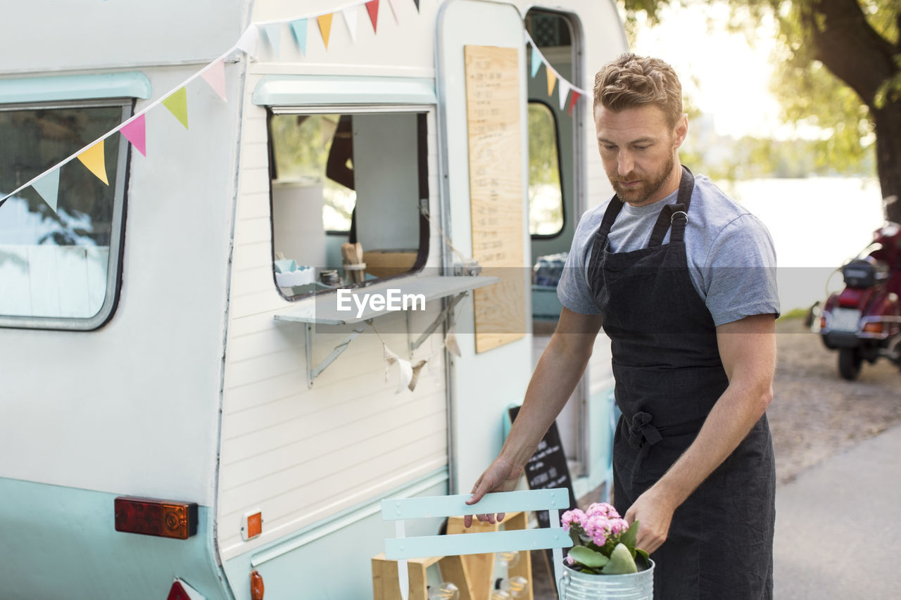 Male owner arranging table outside food truck on street