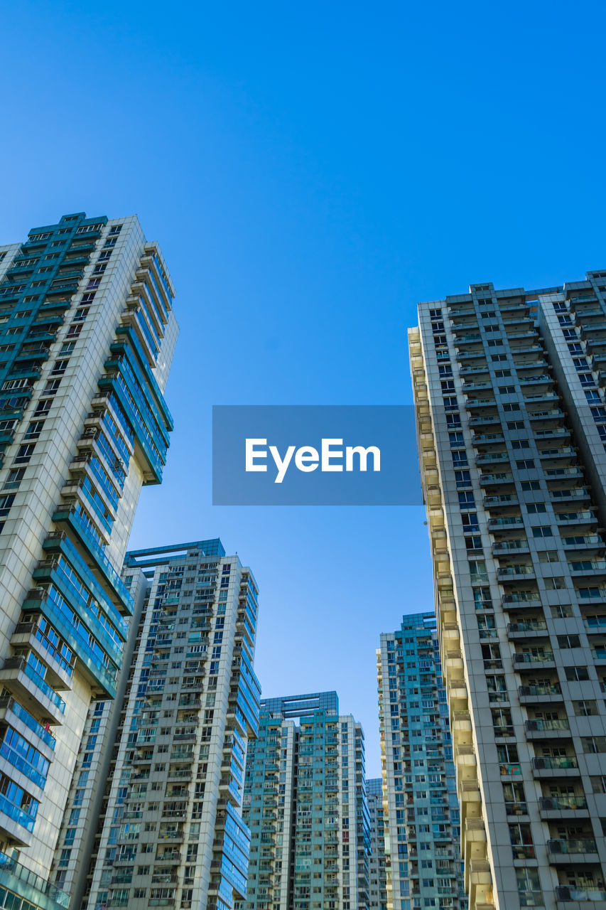 LOW ANGLE VIEW OF BUILDINGS AGAINST BLUE SKY