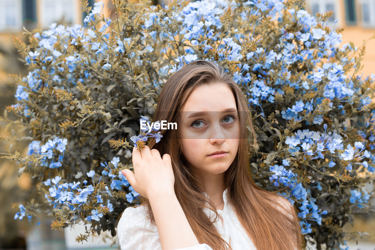 Portrait of young woman sitting against plants