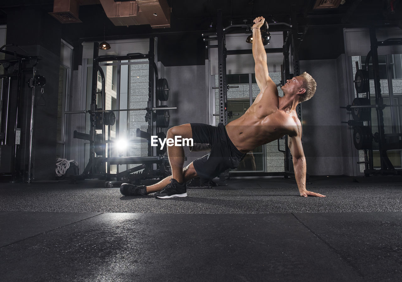 Young man exercising with kettlebell at gym