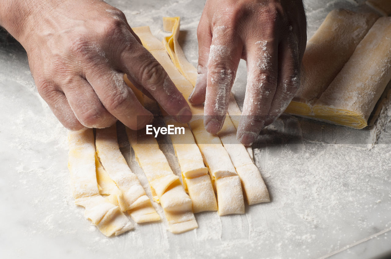 Cropped hands of chef preparing dough on table in commercial kitchen