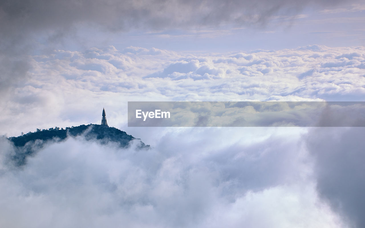 Aerial view of communications tower on hill against clouds