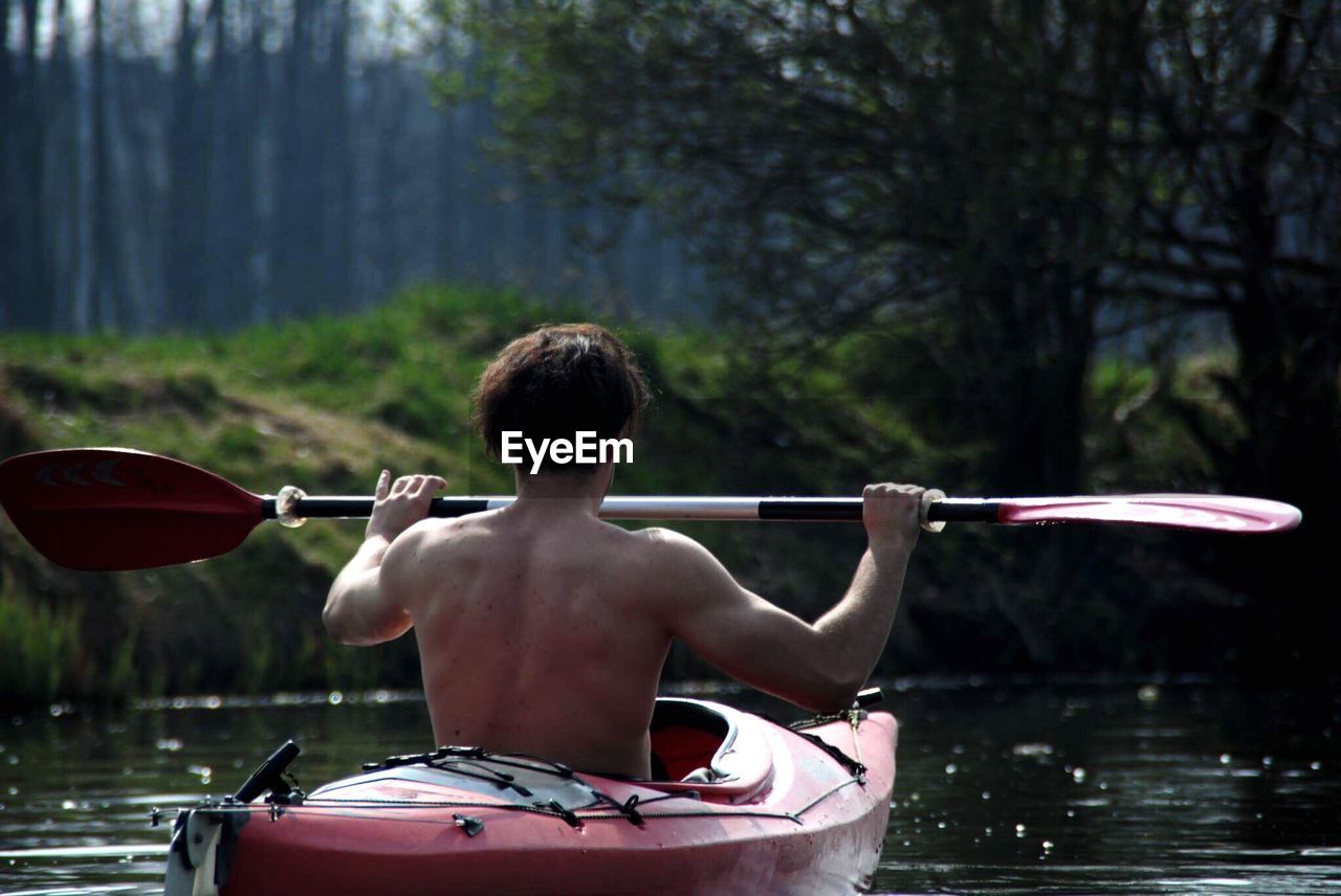 Rear view of man kayaking in lake