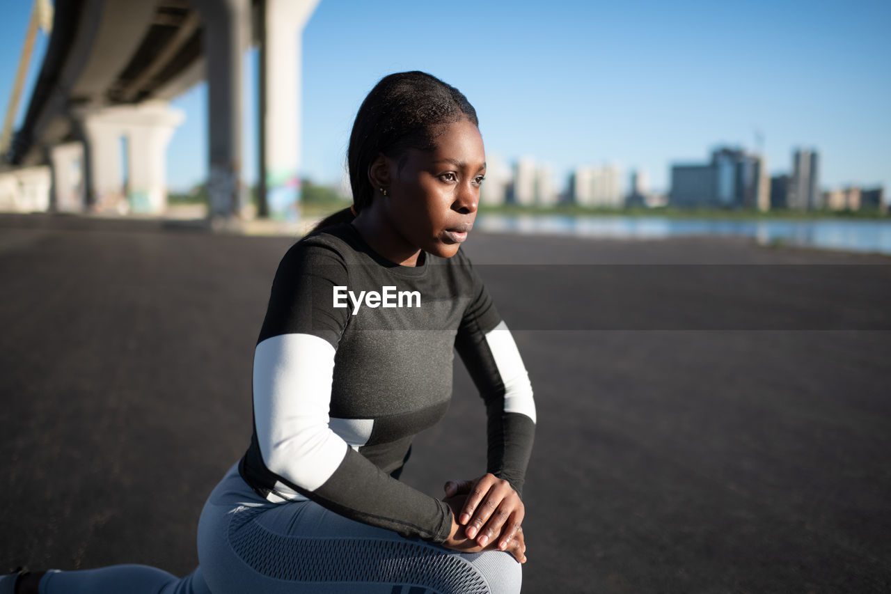 Determined black athlete lunging on street