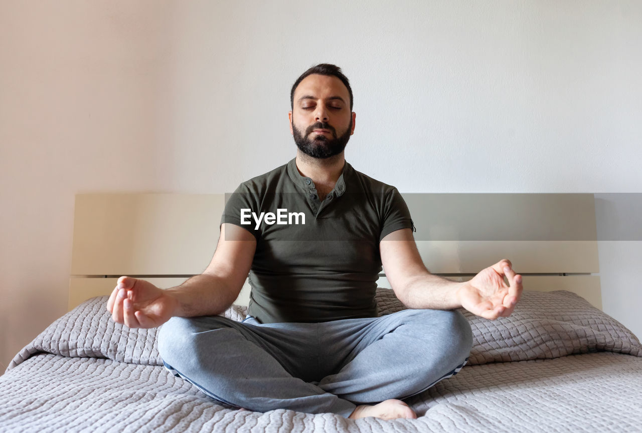 Man meditating on bed at home. zen concept