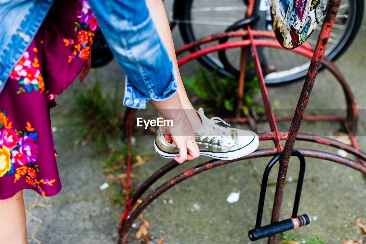 Low section of woman leaning on bicycle rack