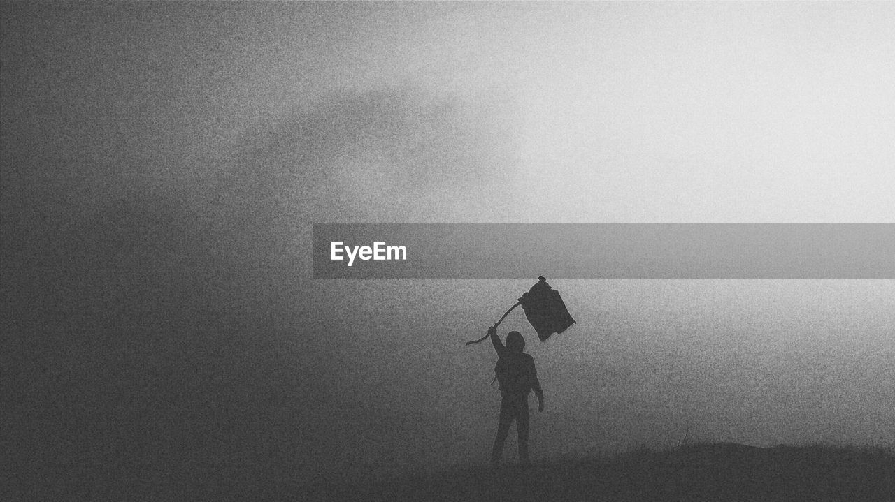 Person holding flag on field during foggy weather