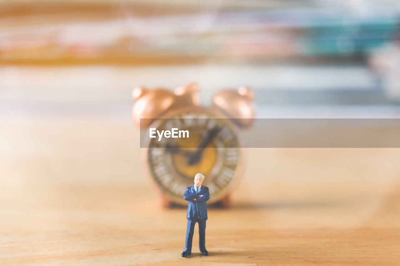 Close-up of figurine against clock on table