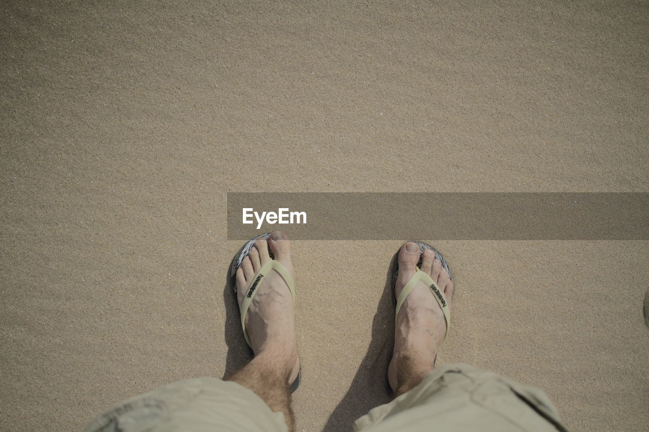 LOW SECTION OF MAN STANDING ON SAND