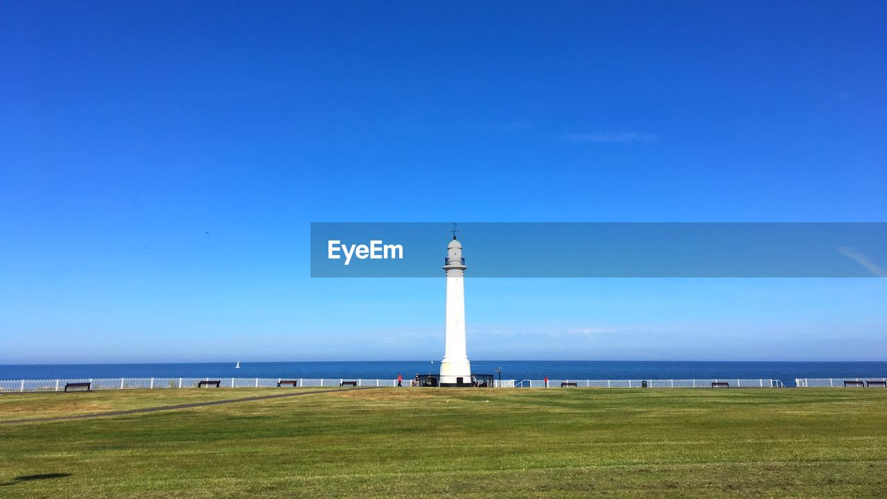 Lighthouse by sea against sky