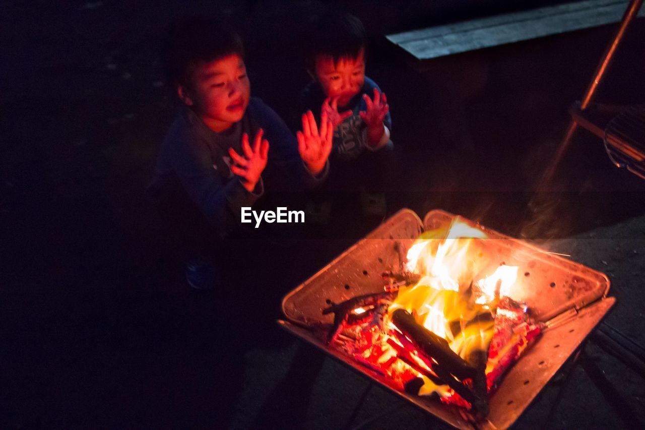 High angle view of kids warming hands by bonfire