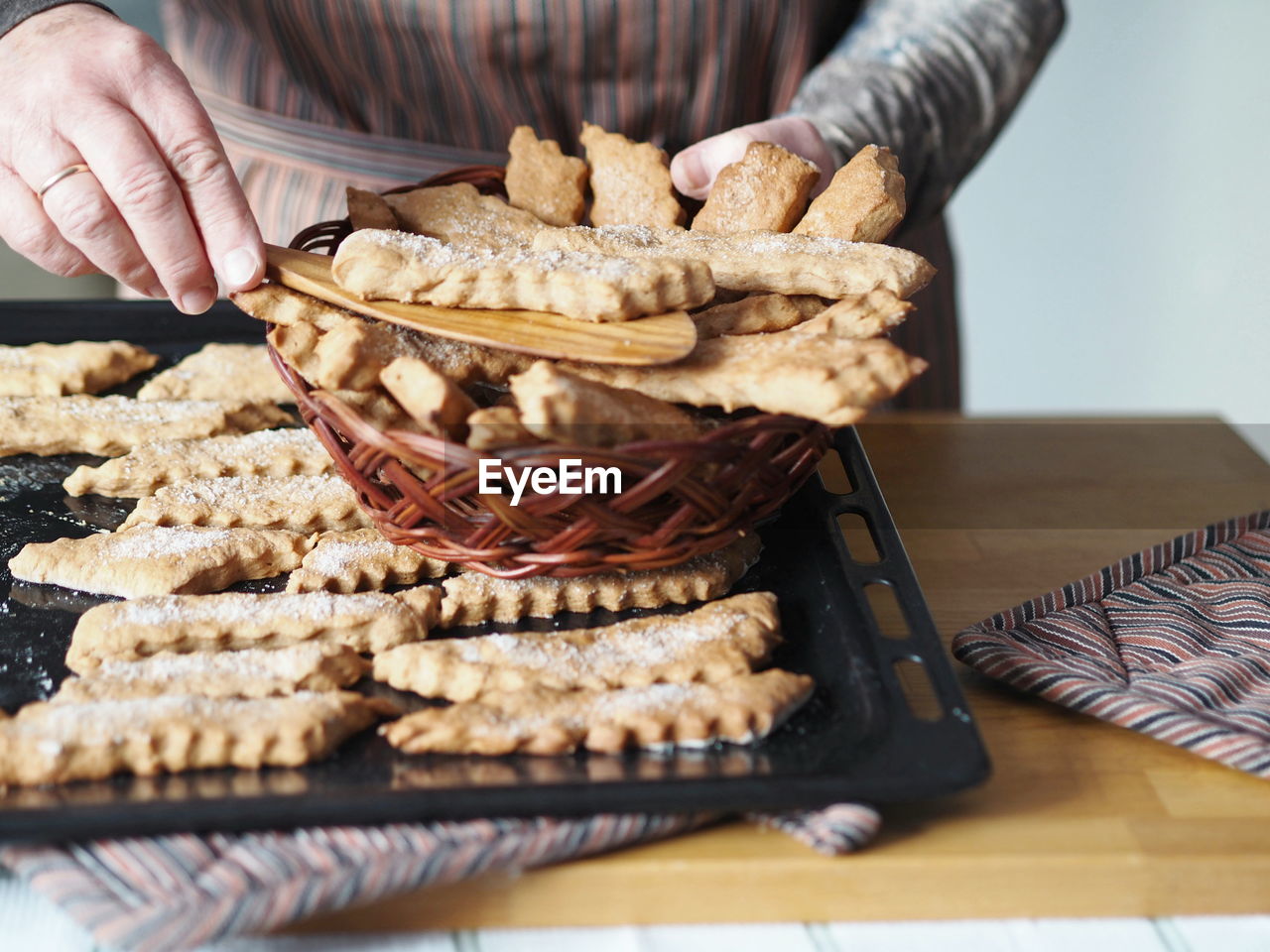  the hands of an elderly woman remove the prepared freshly baked cookies from the baking sheet 