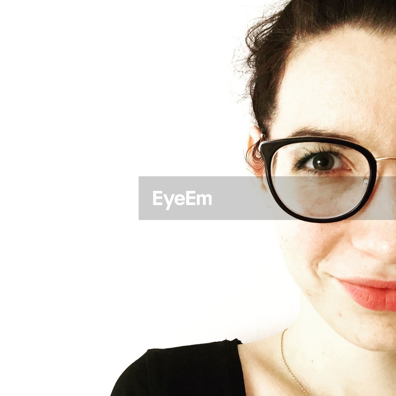 Close-up portrait of young woman in eyeglasses against white background