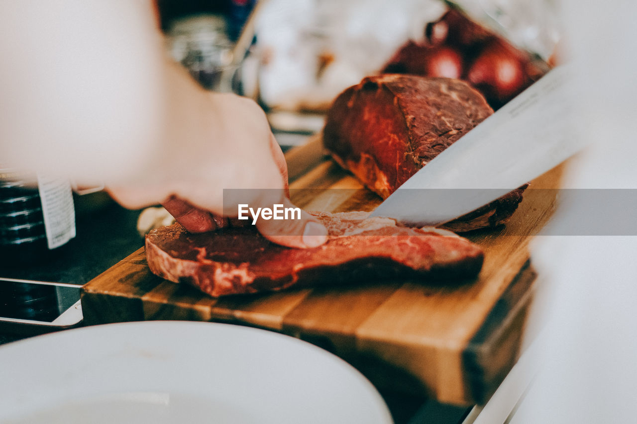 Cropped image of person cutting meat