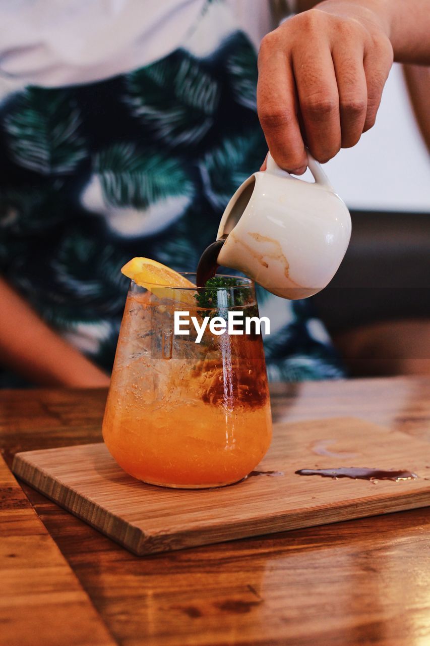 Midsection of man preparing drink at table in cafe