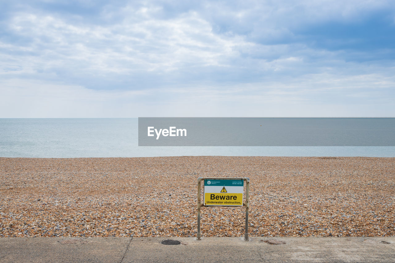 INFORMATION SIGN ON BEACH AGAINST SEA