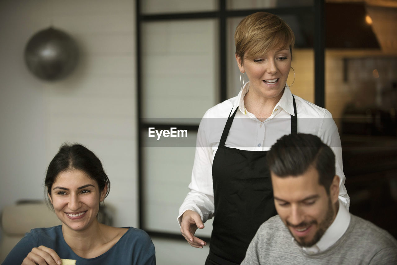 Happy business people and woman wearing apron while winetasting