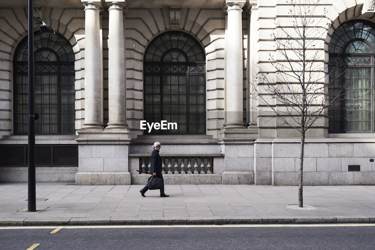 Uk, london, senior businessman walking on pavement in the city