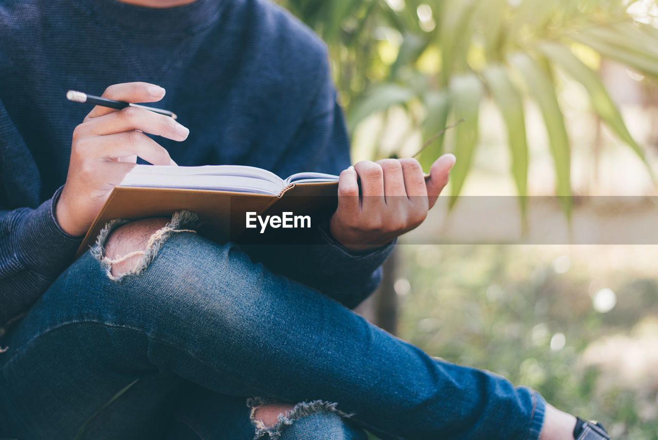 Midsection of man sitting with book