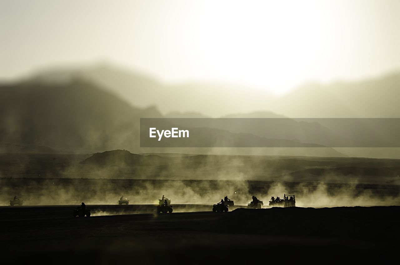 High angle view of silhouette people riding quadbike on field