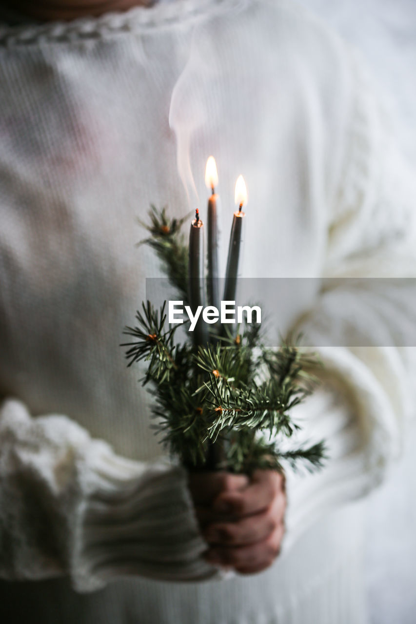 Close-up of woman holding burning candle during christmas