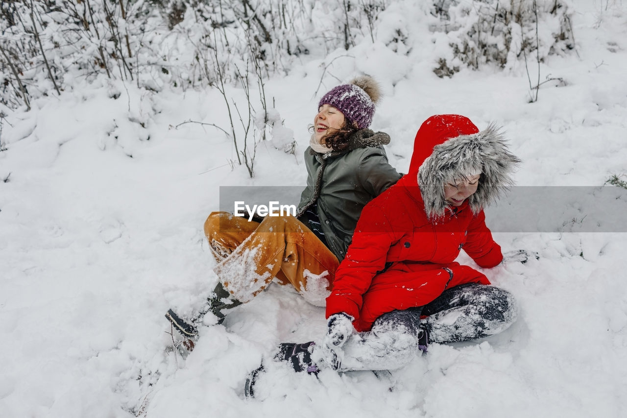 Cheerful sisters playing in snow during winter
