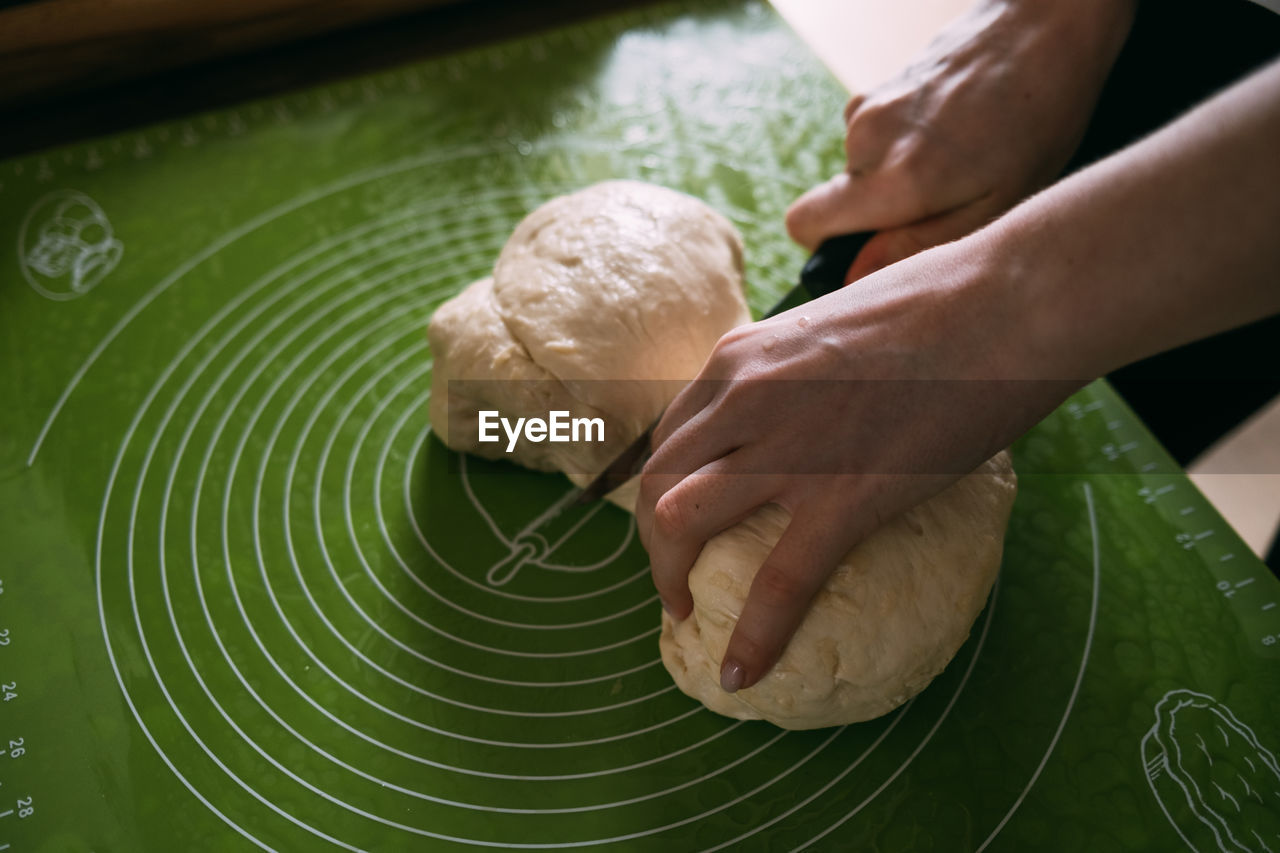 The girl cuts the dough into two parts with a knife. high quality photo