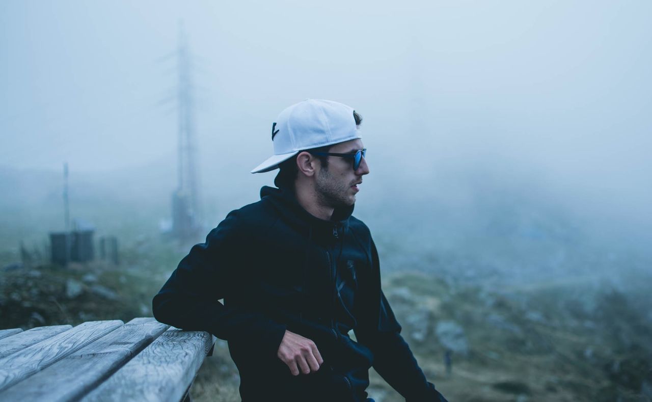 MAN LOOKING AWAY WHILE STANDING ON FOGGY DAY