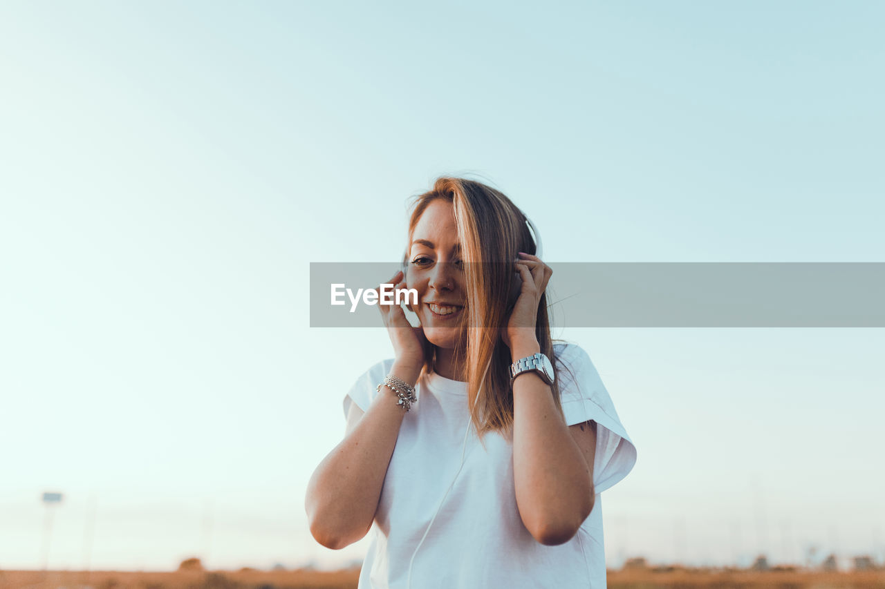 Portrait of smiling young woman against clear sky