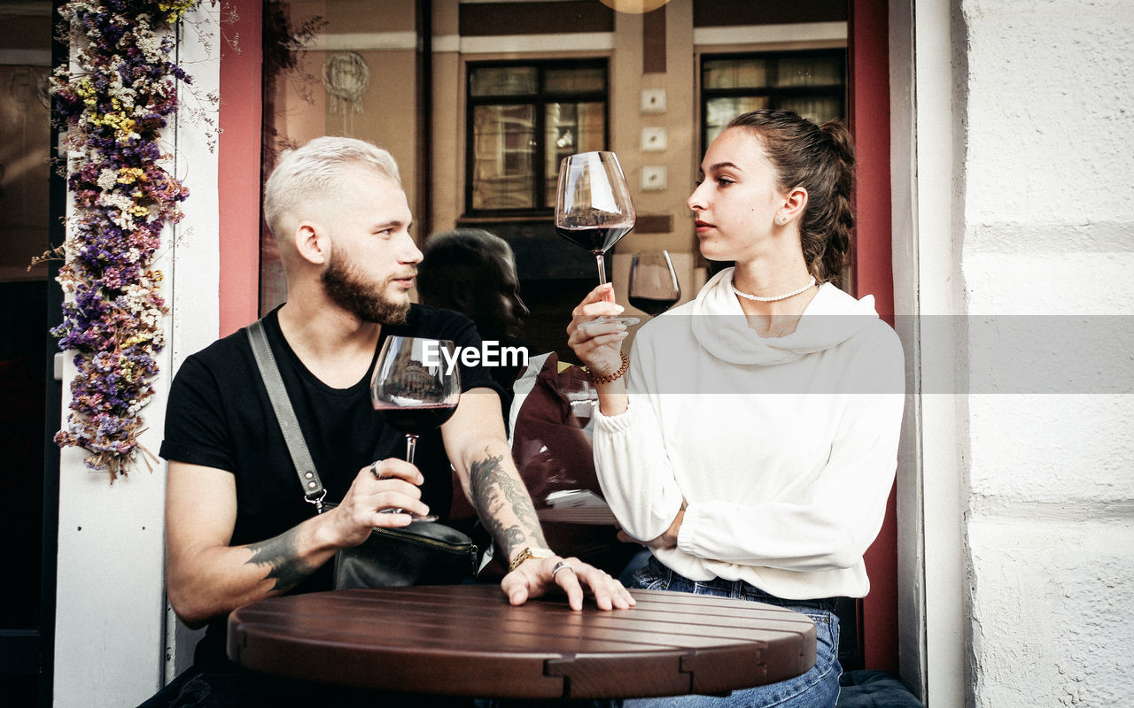 Young couple holding wineglass while sitting at cafe