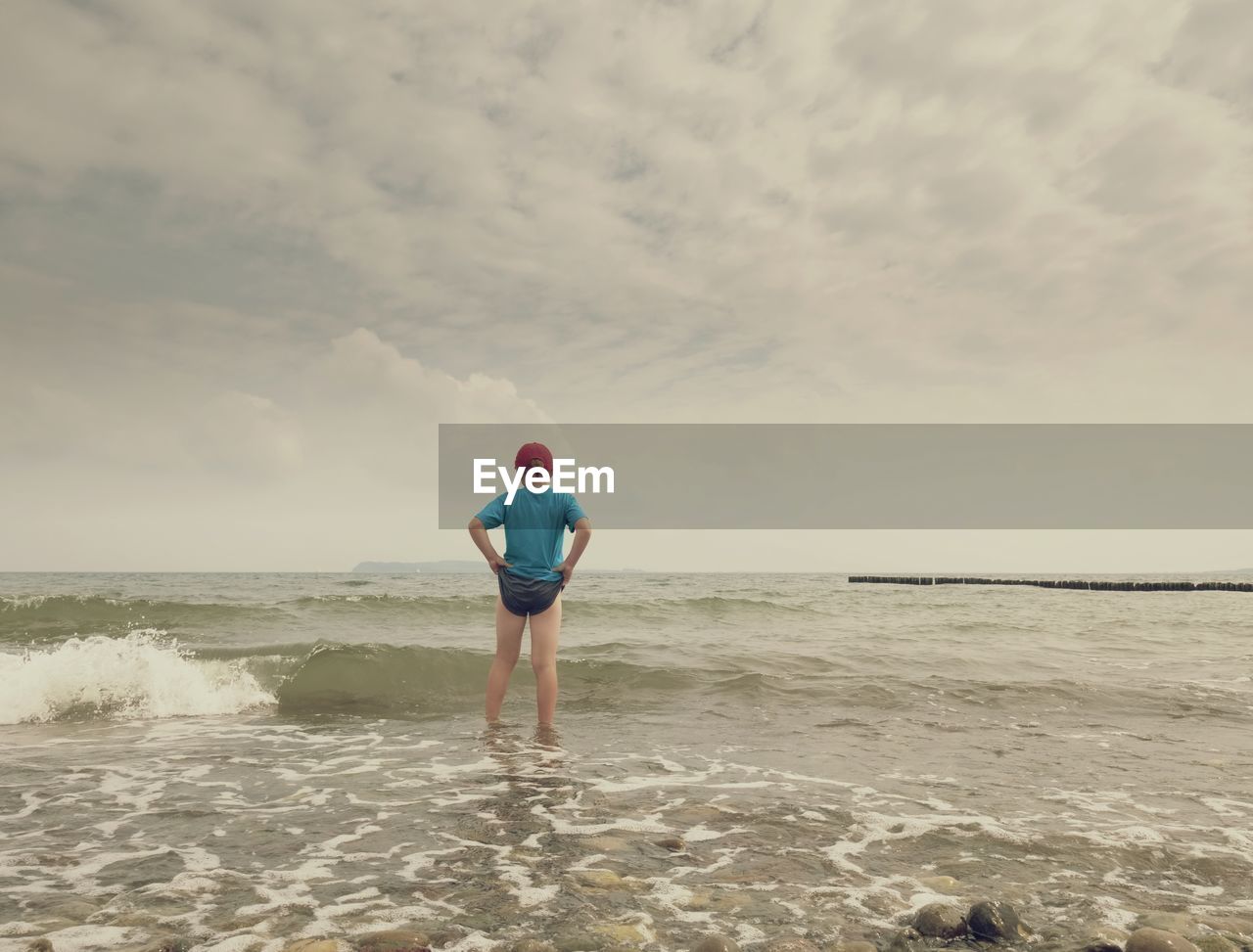 sea, water, beach, sky, land, one person, ocean, shore, sand, body of water, coast, wave, nature, full length, horizon over water, leisure activity, cloud, horizon, beauty in nature, lifestyles, standing, holiday, vacation, adult, rear view, motion, sports, trip, day, wind wave, scenics - nature, outdoors, clothing, tranquility, person, solitude, men, young adult, idyllic, casual clothing, women
