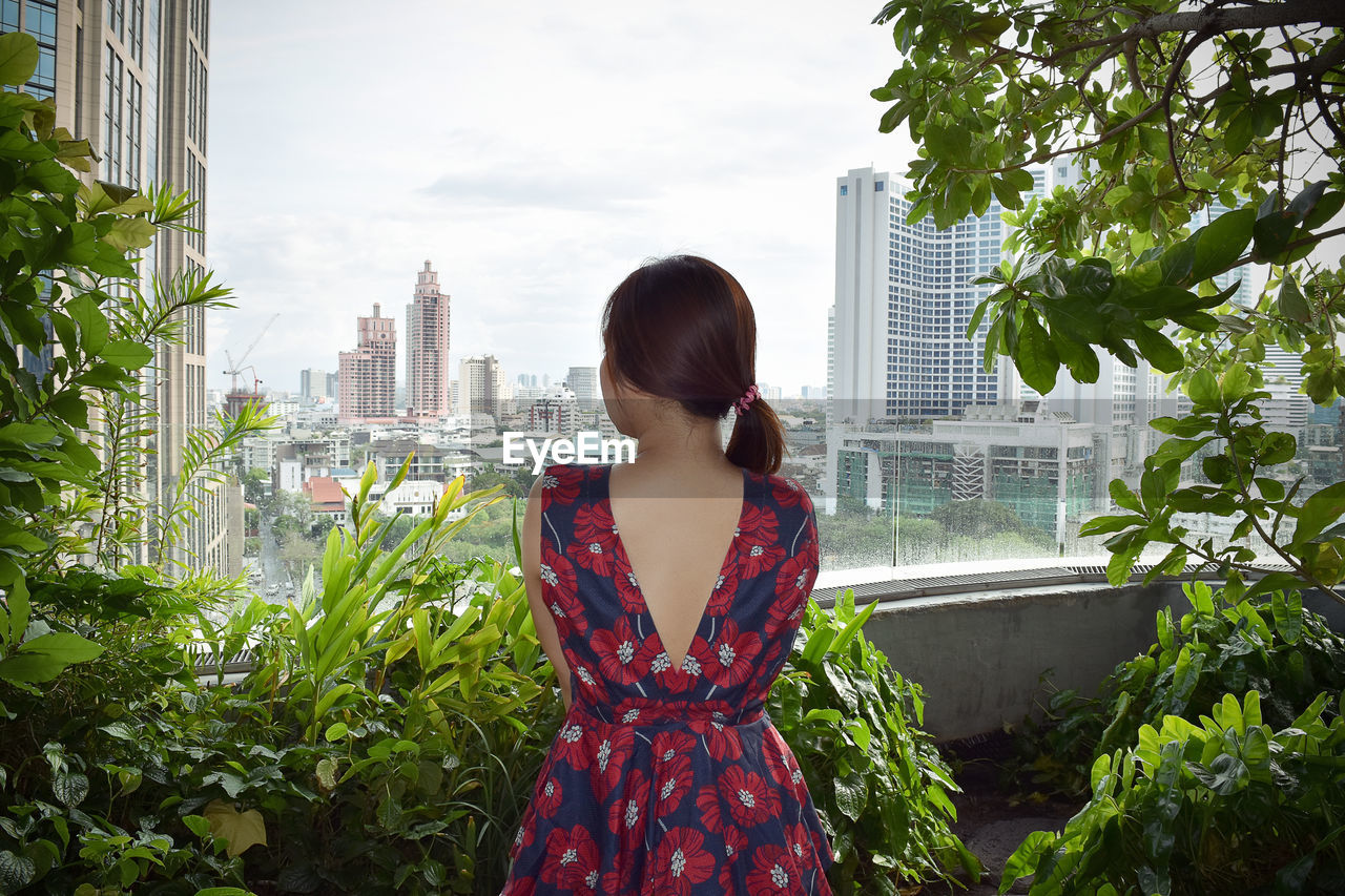 Rear view of woman standing by buildings in city