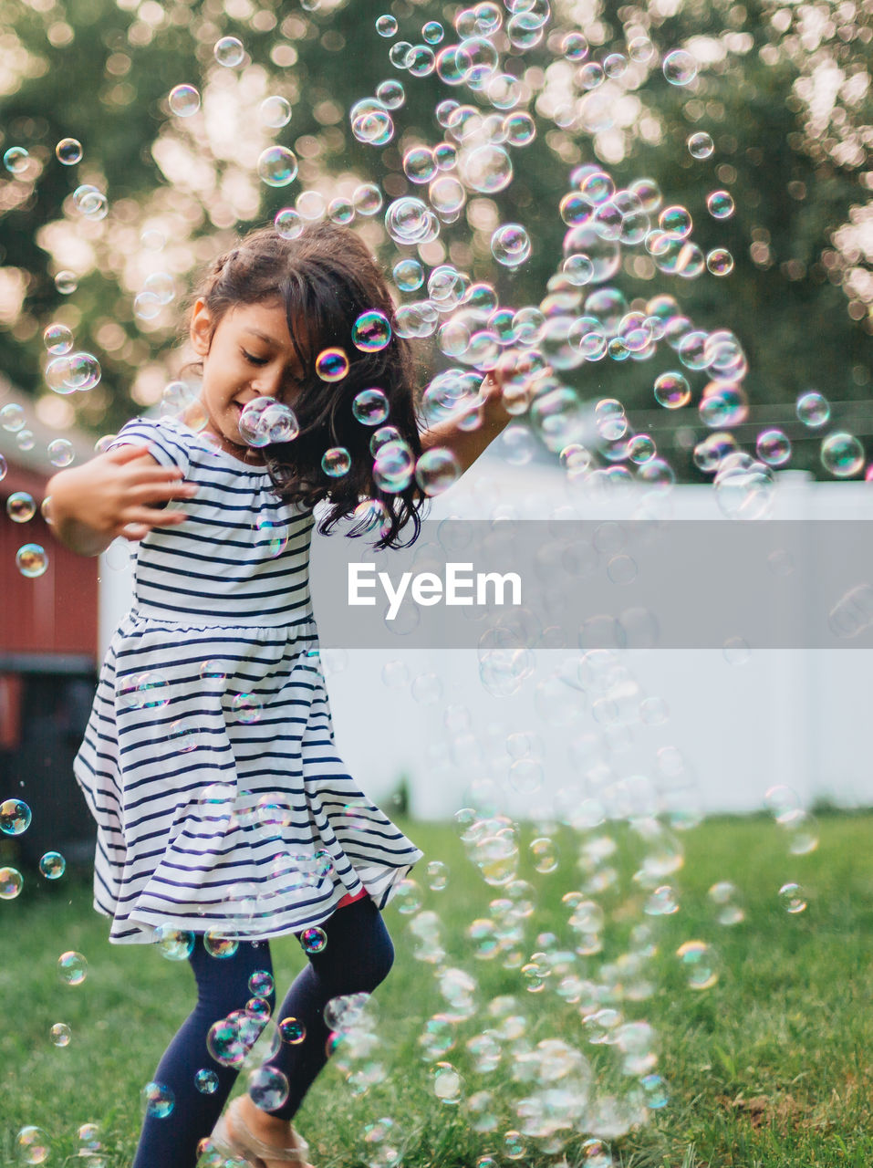 Diverse mixed race pre school age girl at home having fun playing with bubbles on a nice summer day