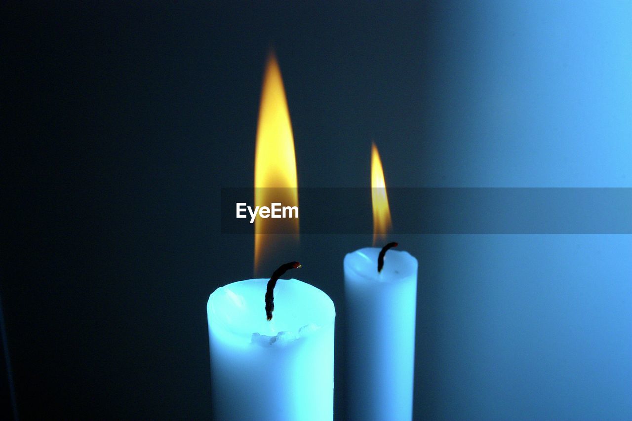 Close-up of lit candles against wall