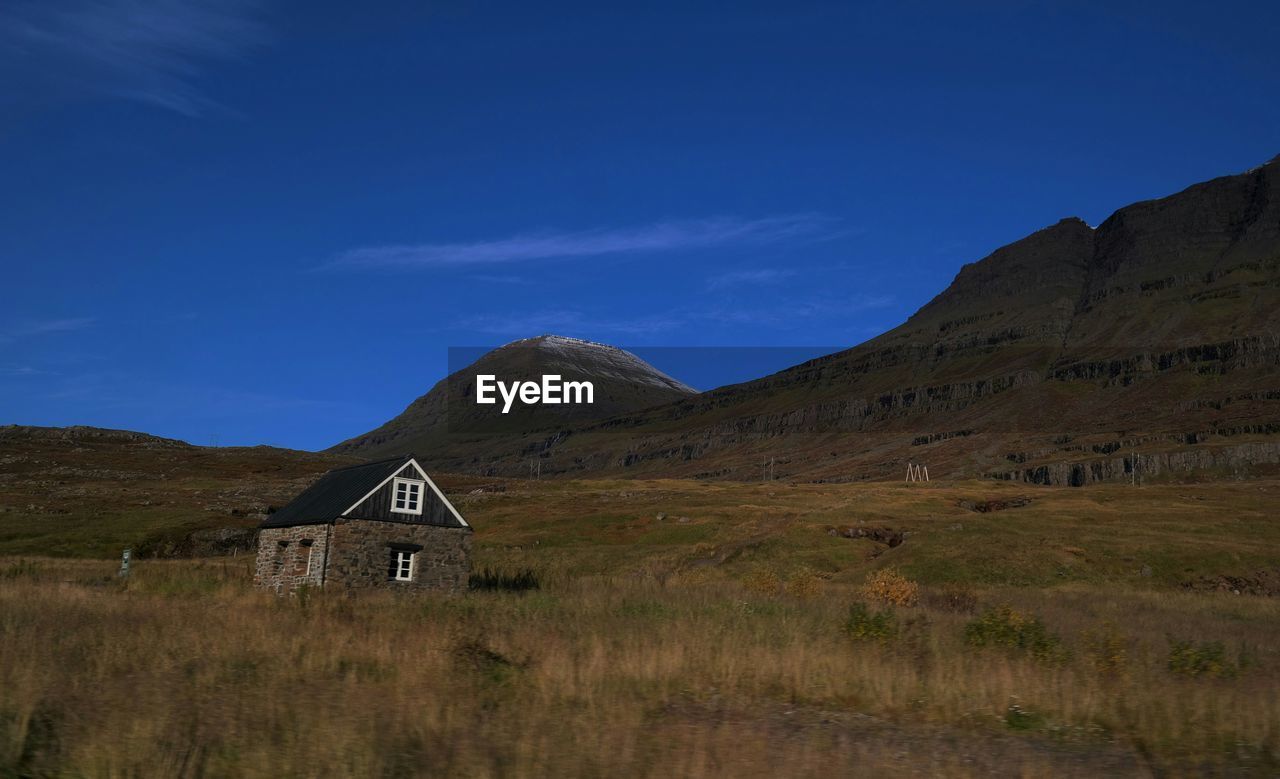 House on grassy field against mountains