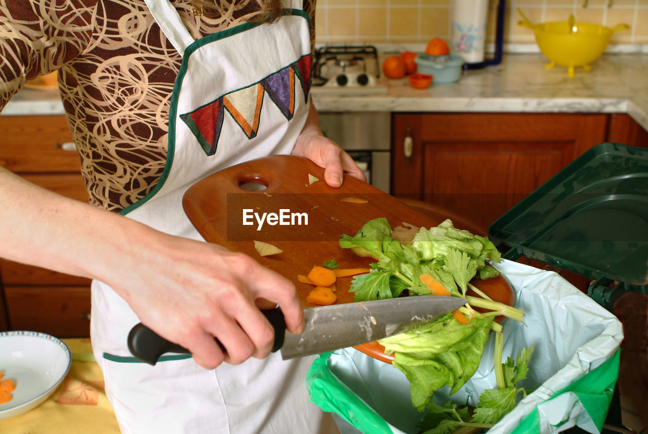 MIDSECTION OF WOMAN PREPARING FOOD AT HOME